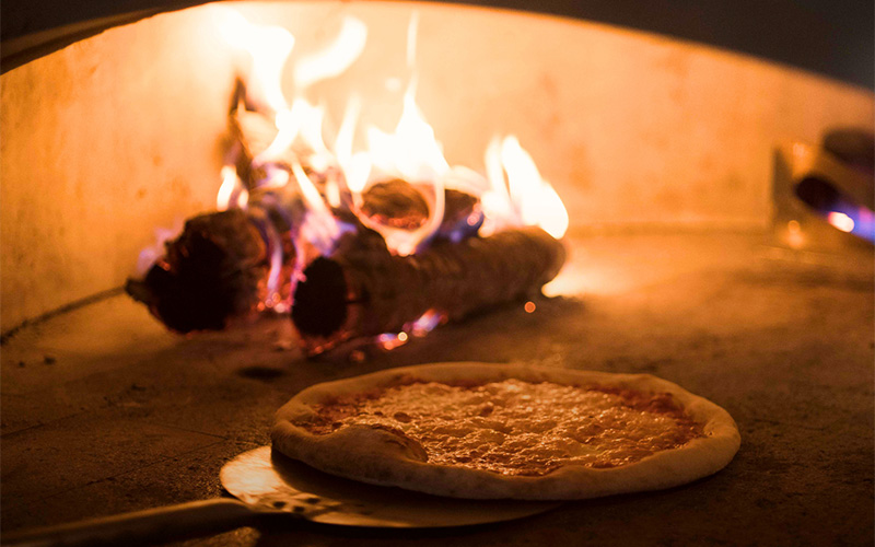 Wood-fired pizza baking in a traditional stone oven