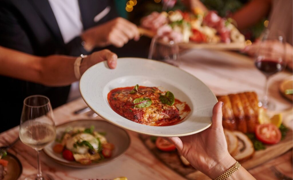 Guests sharing Italian dishes around a dining table at Publico Ristorante.